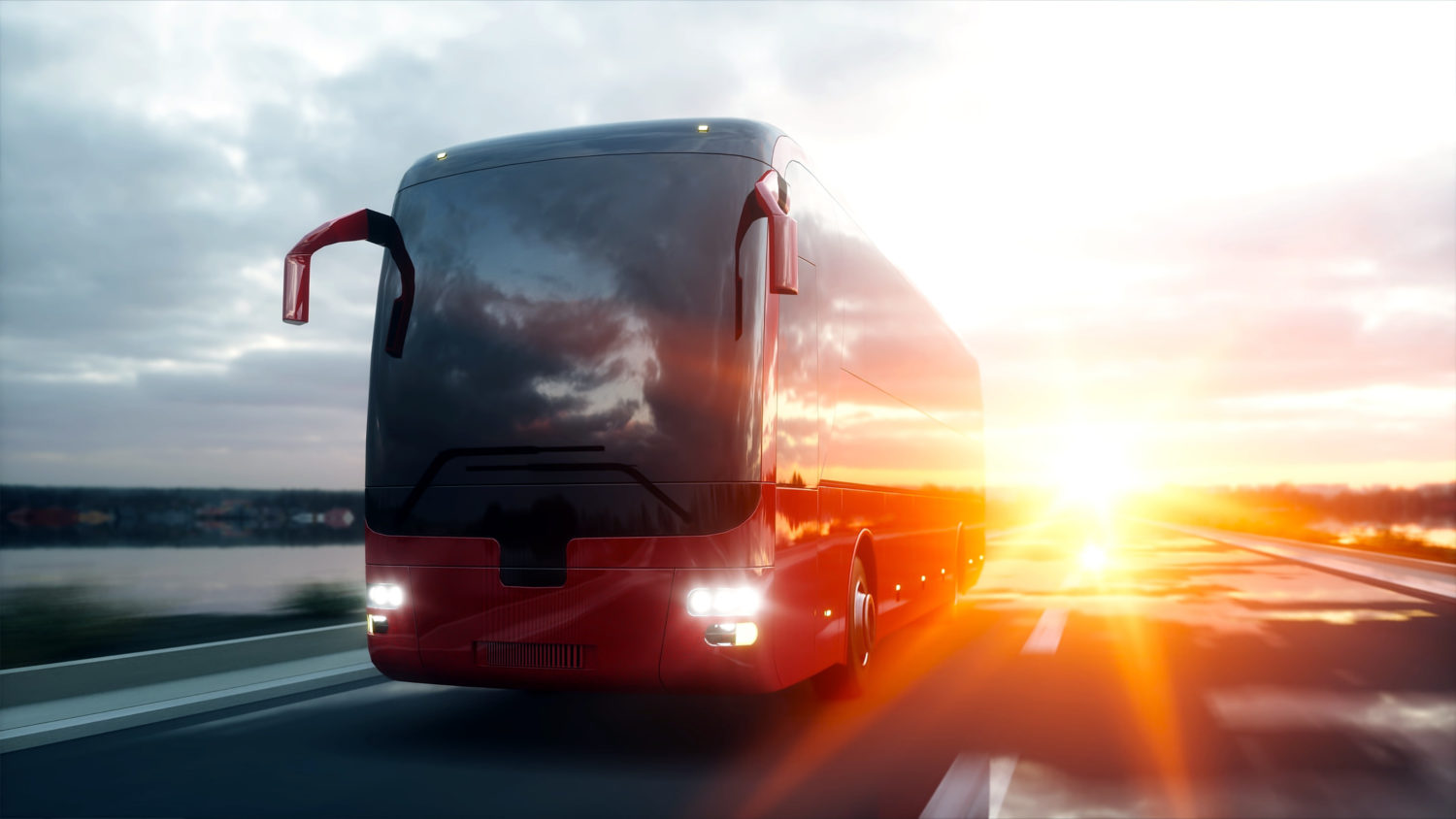 Red bus driving on a road with sunset behind it from Tallinn to Riga